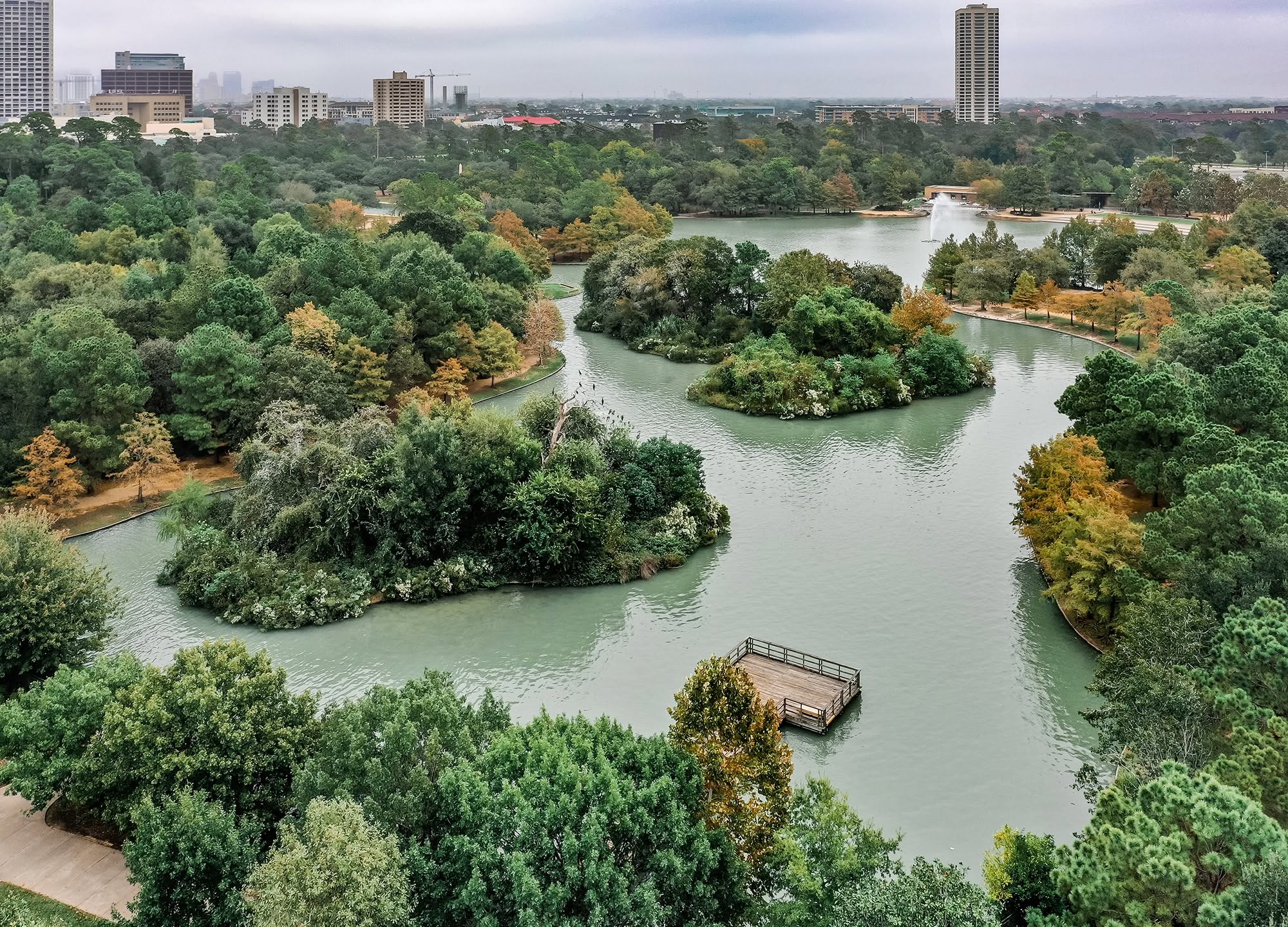 Aerial view of Hermann Park's reflection pool, islands, and Museum District skyline beyond
