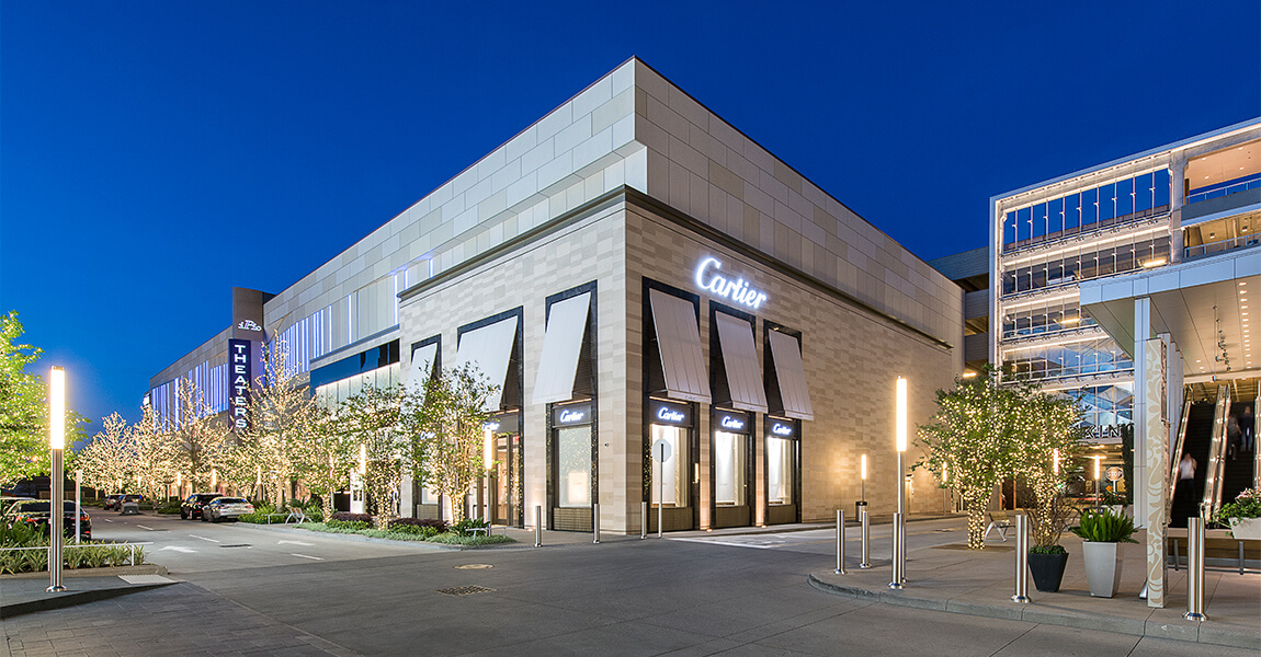The Cartier flagship at River Oaks District at blue hour, with the iPic Theaters tower and illuminated tree-lined drive